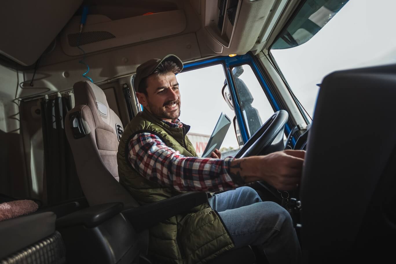 male driver sitting in his truck, using his tablet