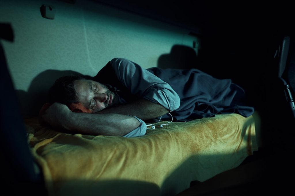 truck driver sleeping on cabin's bed at night