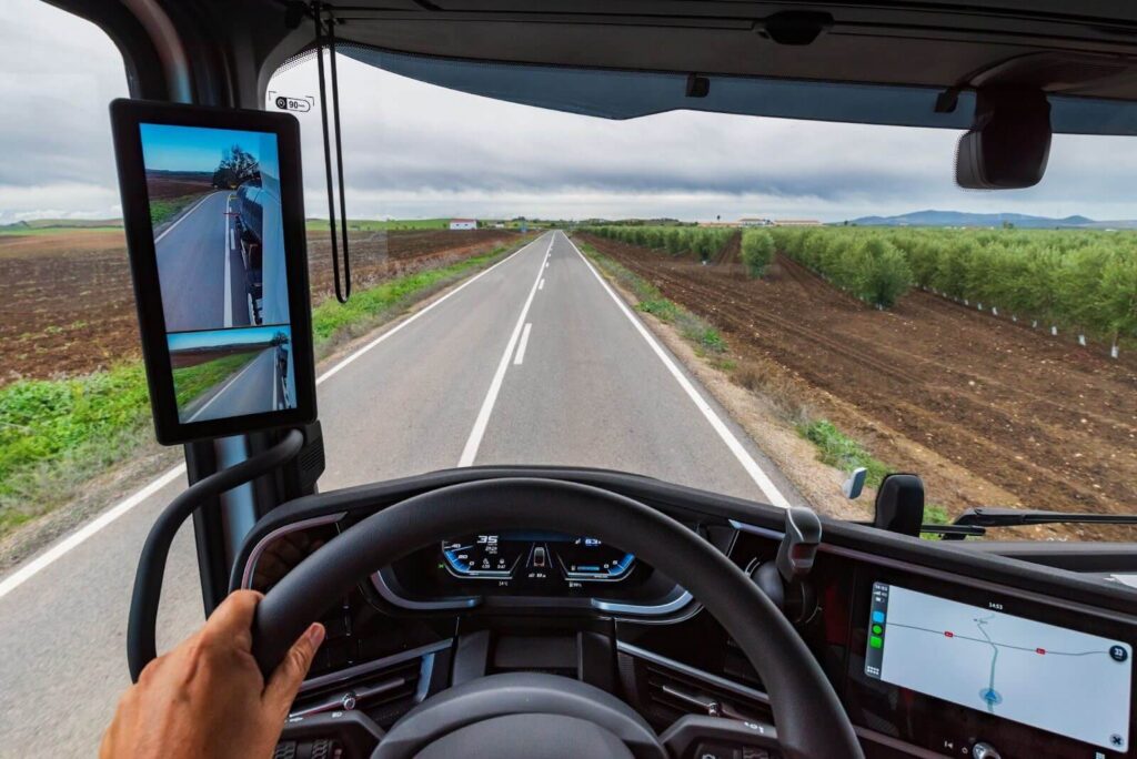 view from the driver's position of a truck on a road in the middle of crop fields and the driver guided by gps