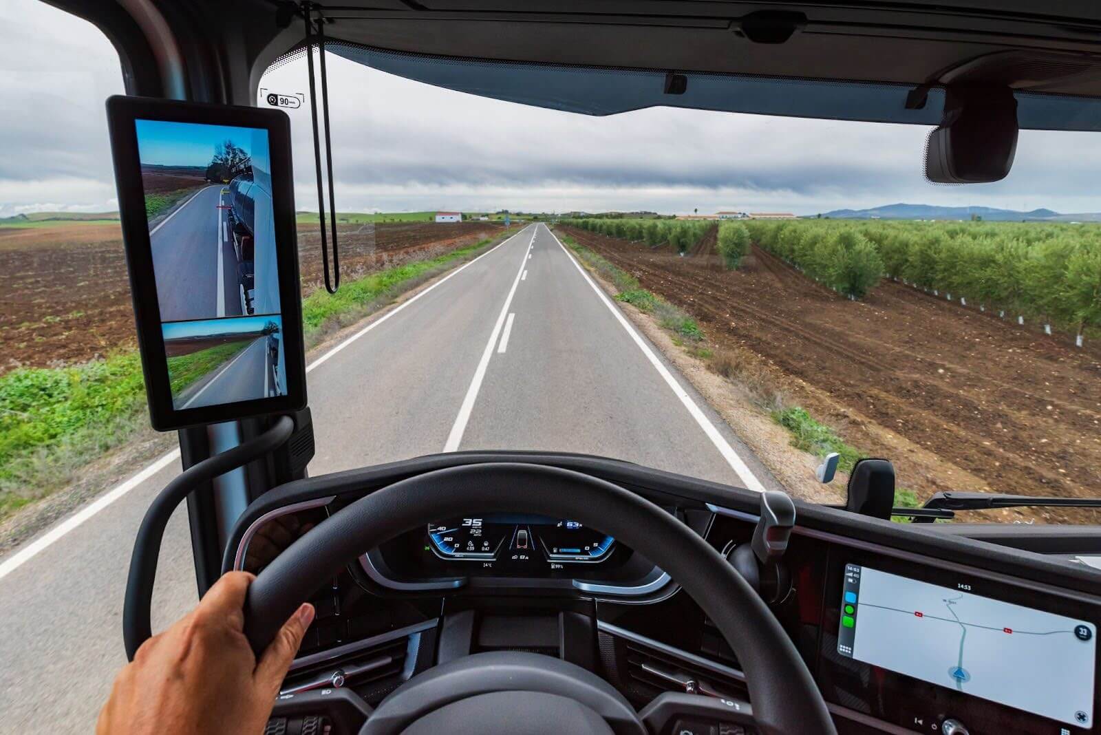 view from the driver's position of a truck on a road in the middle of crop fields and the driver guided by gps